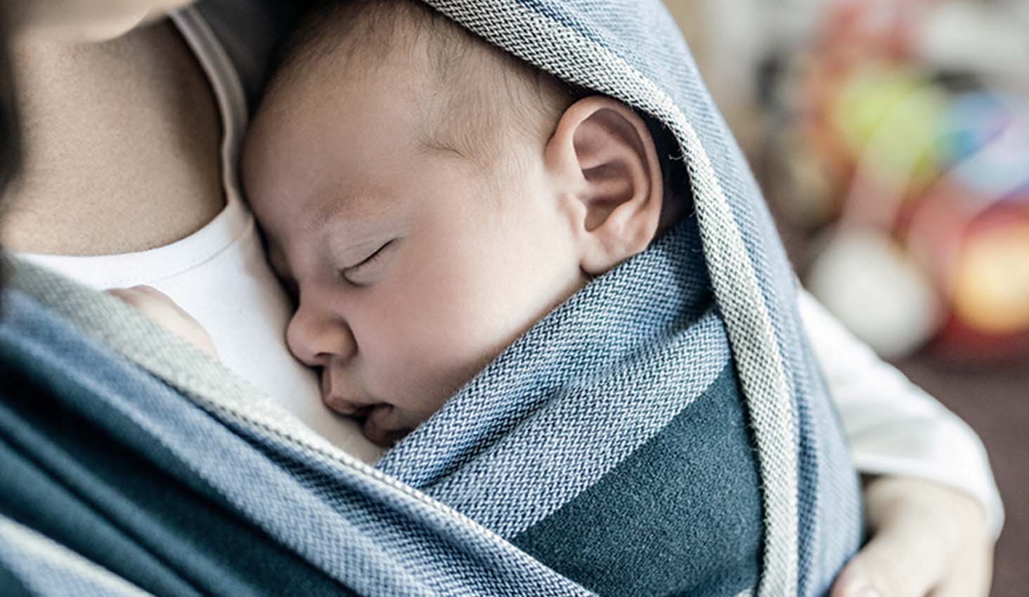Bebé duerme profundamente en el pecho de su madre en un rebozo