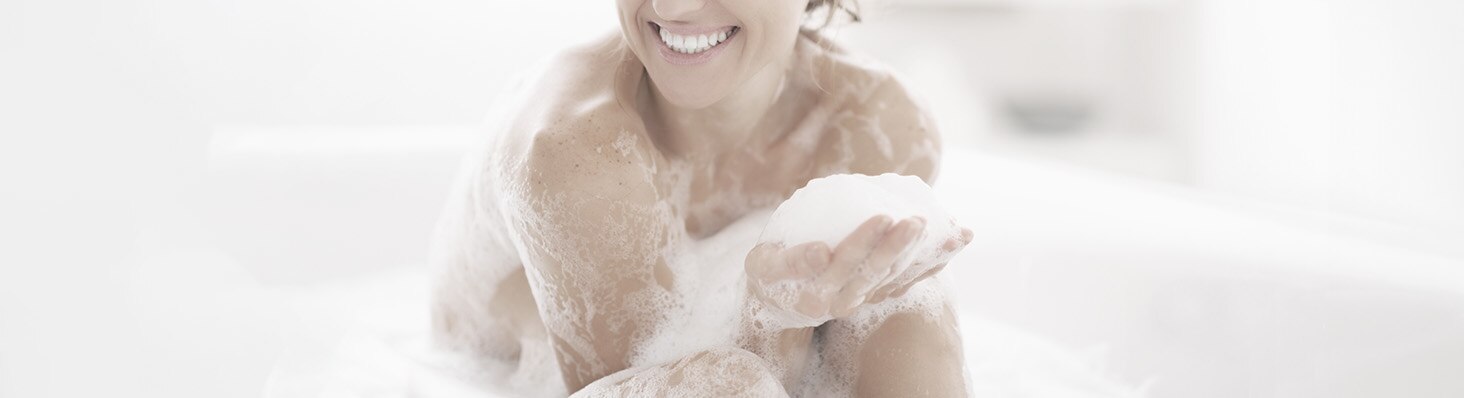 Mujer sonriendo mientras toma un baño de espuma 